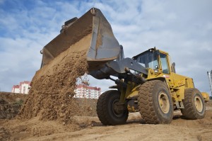 Wheel loader machine unloading sand at eathmoving works in construction site